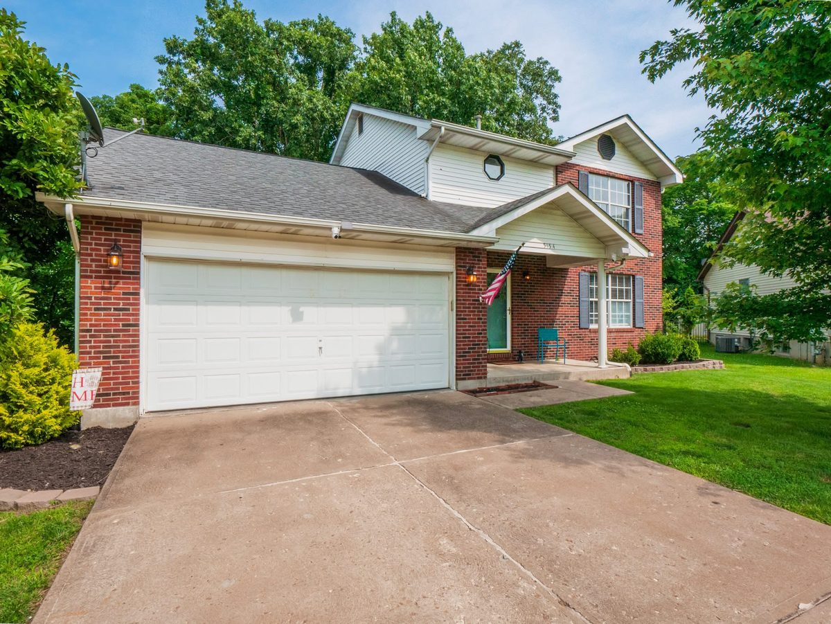 Brick and vinyl two-story with a covered front porch and two-car garage in Jefferson County, Missouri